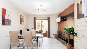 A modern living room with a dining area, a TV, and a potted plant. - Apartment in Castle Harbor, heated pool, satellite TV channels (Los Cristianos)