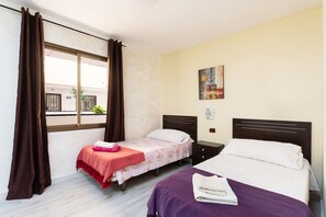 Une chambre avec deux lits, une fenêtre avec des rideaux, un tableau au mur et une petite table.