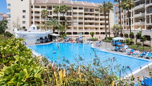 A hotel with a large swimming pool, multiple balconies, and palm trees. - Apartment in Castle Harbor, heated pool, satellite TV channels (Los Cristianos)