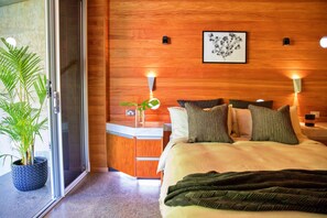 Una habitación de hotel con cama, mesitas de noche, una planta en maceta y una pared de madera.