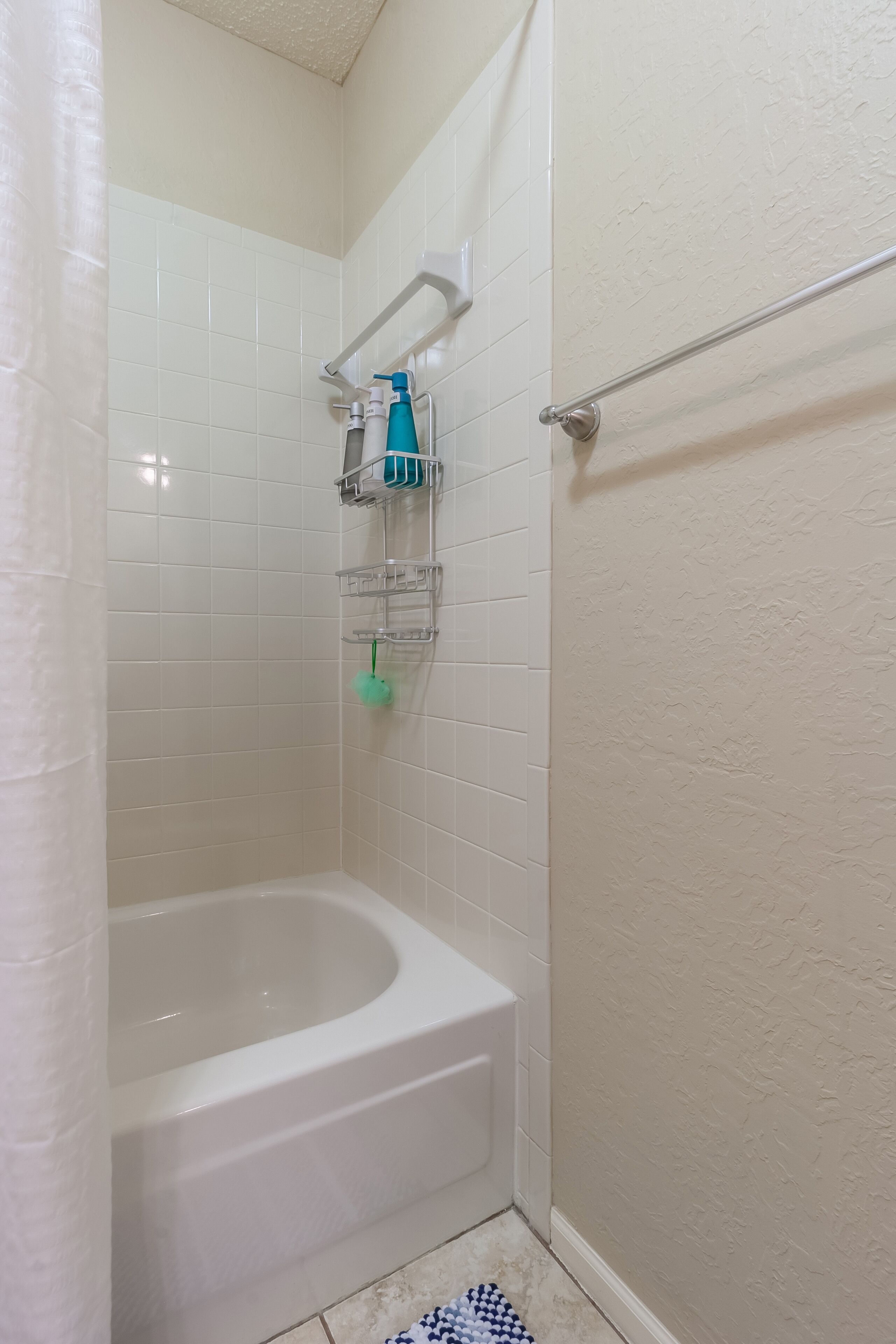 Ein Badezimmer mit einer weißen Badewanne, einer Duschkabine und einem Handtuchhalter.