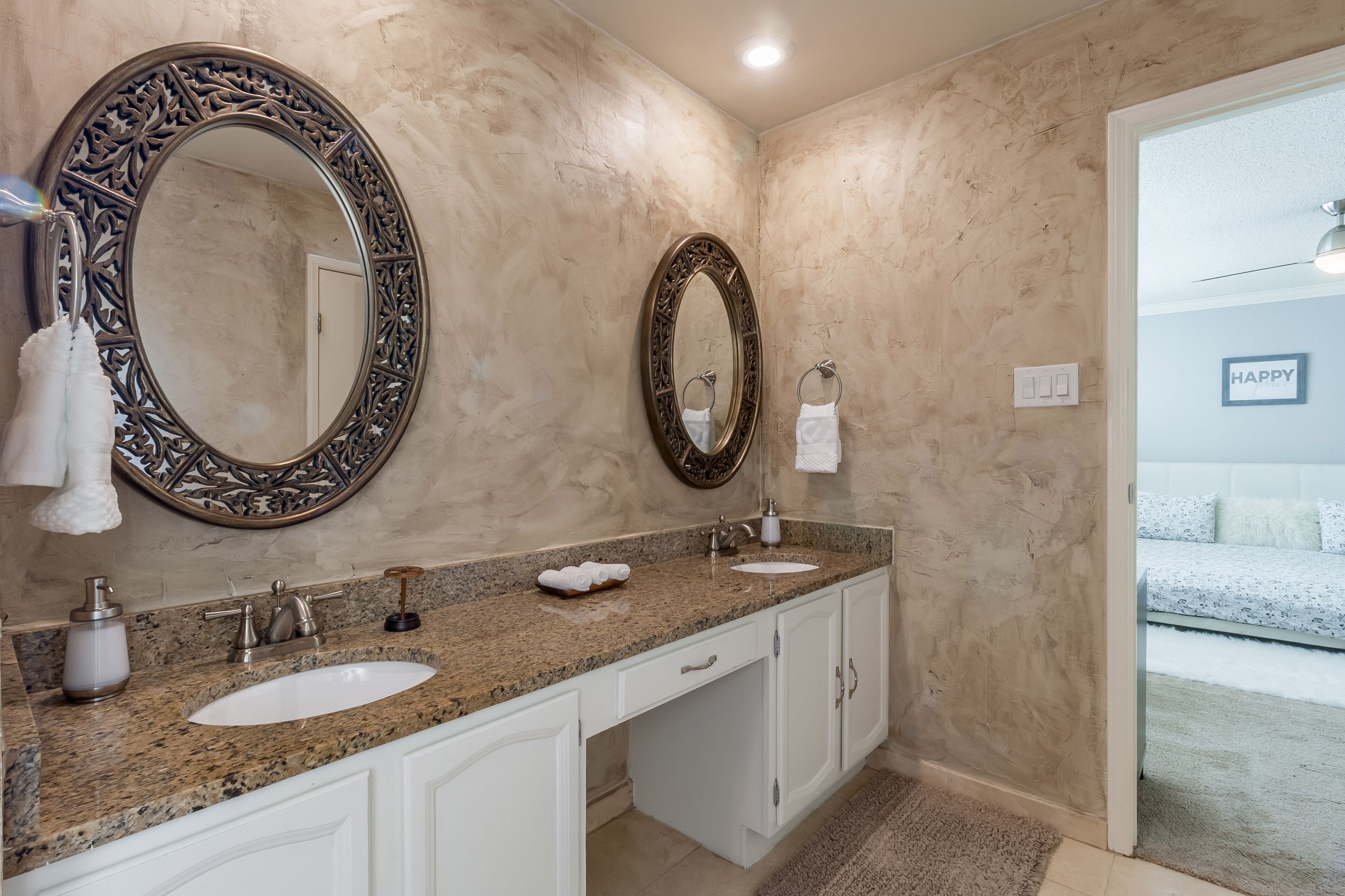 Une salle de bain avec deux lavabos, un grand miroir décoratif et un porte-serviettes.