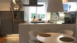 A modern kitchen with an island, white chairs, and a round table. - very quiet apartment close to the sea and the center (Überlingen)
