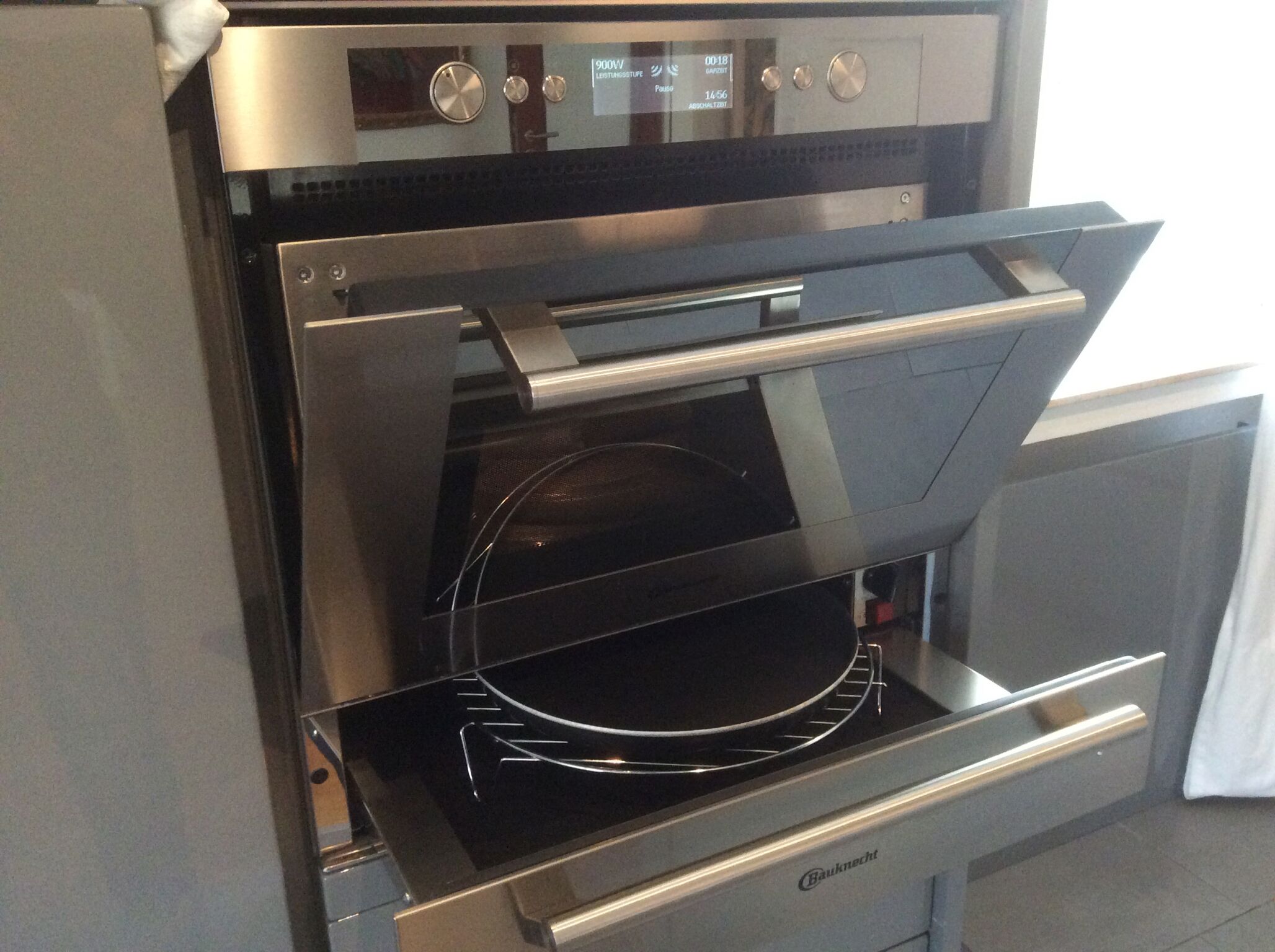 An open modern oven with digital controls and a glass door.