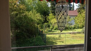 A balcony with a view of a garden, a hanging lantern, and a metal railing. - very quiet apartment close to the sea and the center (Überlingen)