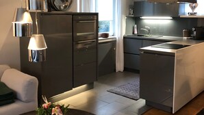 A modern kitchen with a central island, built-in appliances, pendant lighting, and a view to the outside. - very quiet apartment close to the sea and the center (Überlingen)