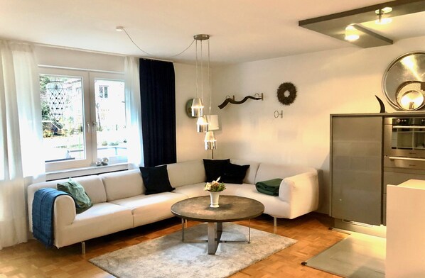 A modern living room with a white sofa, a round coffee table, and a built-in refrigerator.