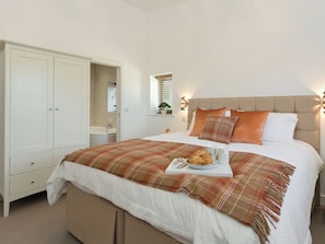Quarto com cama, guarda-roupa, banheiro e janela com persianas.