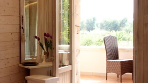 Ein Badezimmer mit Holzvertäfelung, einem Spiegel, einem Waschbecken und einem Stuhl am Fenster.
