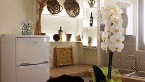 Eine Küche mit Kühlschrank, Korbwägelchen, Blumen in einer Vase und einem Spülbecken.