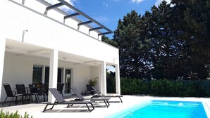 A modern house with a pool, outdoor seating, and a covered patio area. - Aria, villa in Filipana, close to numerous beaches and activities (Marcana)