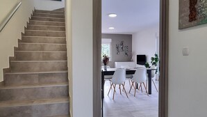 A staircase leading to a dining area with a modern design, a flat-screen TV, and a minimalist decor. - Aria, villa in Filipana, close to numerous beaches and activities (Marcana)