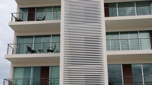 Een meerlaags gebouw met balkons, grote ramen en een centrale verticale structuur.