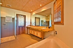 Un baño con bañera, un espejo grande y una zona de ducha.