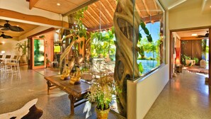 A modern interior with a glass wall offering a view of a pool and lush greenery. - Casa Albero Via Roma (Surfers Paradise)