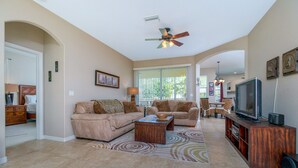 A spacious living room with two sofas, a coffee table, and a television on a wooden stand.
