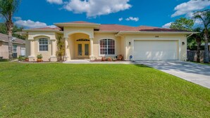 A two-story house with a garage, a well-maintained lawn, and a clear blue sky.