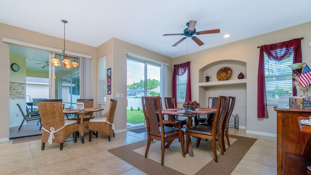 A dining area with a table and chairs, a ceiling fan, and a view of the outdoors.