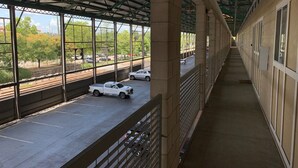 Überdachter Fußweg mit Blick auf eine Straße und parkende Autos.