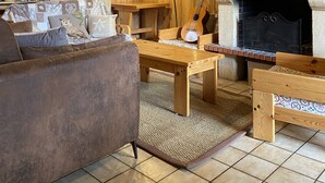 Un intérieur chaleureux en bois, avec une cheminée, un canapé, une table basse et une bibliothèque.