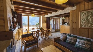 L’intérieur chaleureux d’un chalet en bois comprend un coin repas, un canapé et une grande fenêtre donnant sur les montagnes.