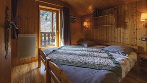 Une chambre à coucher dans une cabane en bois, avec un lit, une fenêtre, un radiateur et une étagère remplie de livres.