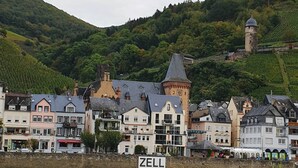 Un pueblo a orillas del río con edificios históricos, una torre destacada y un cartel que dice 'ZELL'.