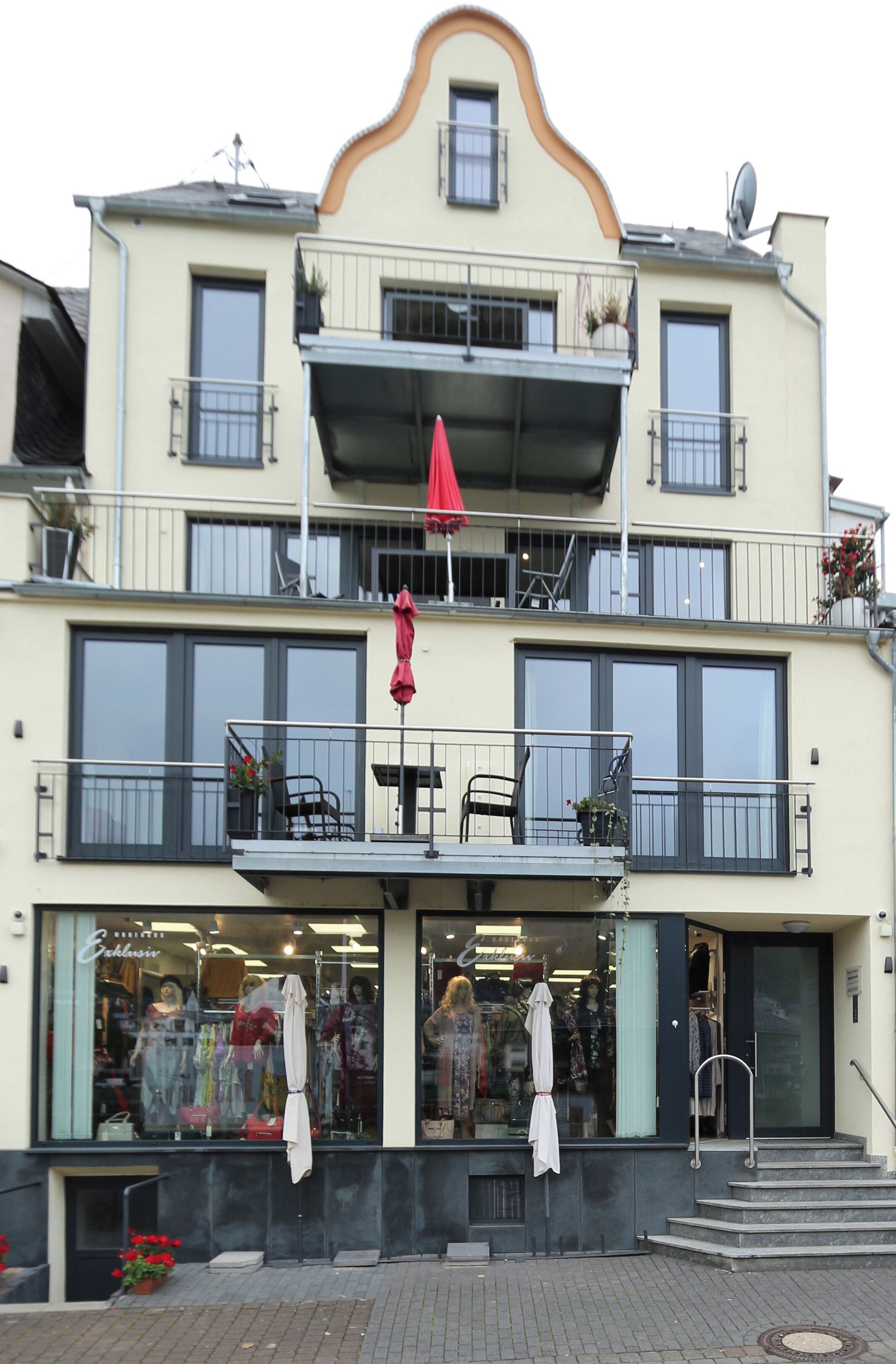 A multi-story building with balconies, a storefront, and a staircase leading to the entrance.