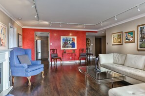 Relax in this stylish living room with a bold accent wall, a blue armchair, a white sofa, and a glass coffee table.