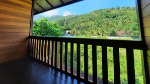 A wooden balcony with a view of a lush green landscape and a small building. - Hotel Besar Bulan Baru - Senggigi (Senggigi)