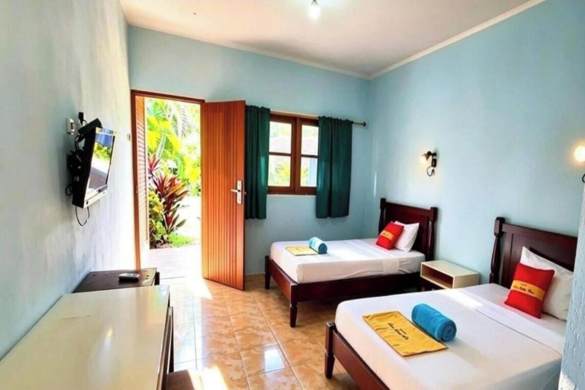 A hotel room with two beds, a desk, a TV, and a window with curtains.