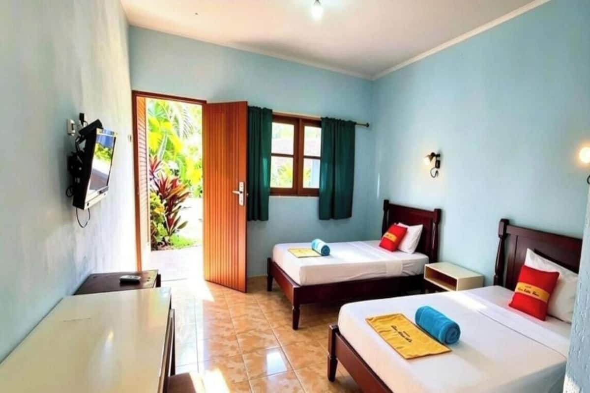 Habitación de hotel con dos camas, un escritorio, un televisor y una ventana con cortinas.