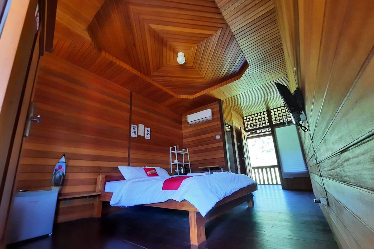 A wooden room with a bed, a ladder, and a small table.