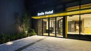 The exterior of the Smile Hotel with a modern design, featuring large glass doors and a well-lit entrance.