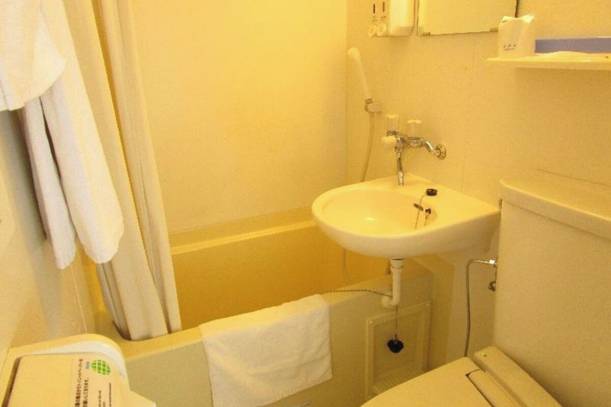 Un baño con un lavabo blanco, un espejo y una toalla colgada en la pared.