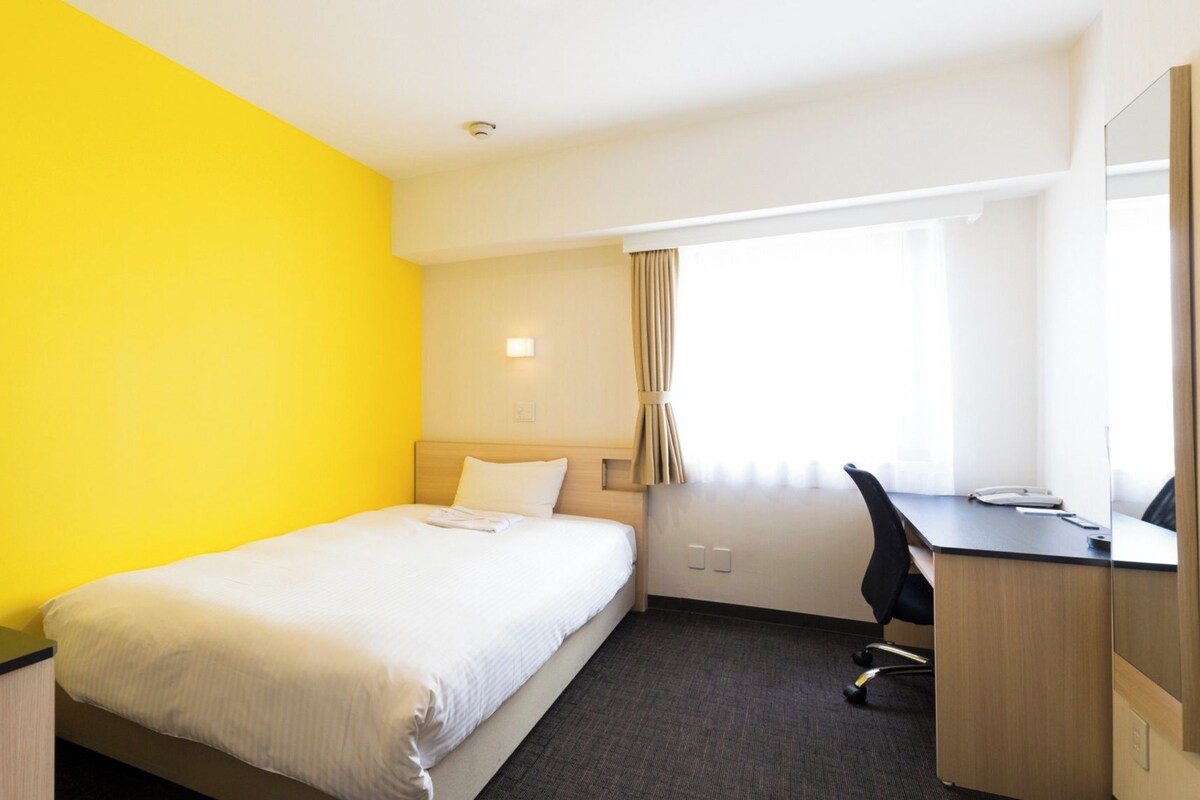 Una habitación de hotel con cama, escritorio, silla y televisión.