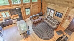 Una cabaña espaciosa con cocina, comedor y sala de estar. Cuenta con ventanas amplias, chimenea y una zona de estar acogedora.