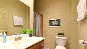 Une salle de bain avec un lavabo blanc, des meubles en bois, des toilettes et un rideau de douche.