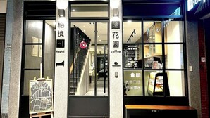 A hotel entrance with a signboard for a hidden cafe, a staircase, and a coffee shop visible through the glass doors.