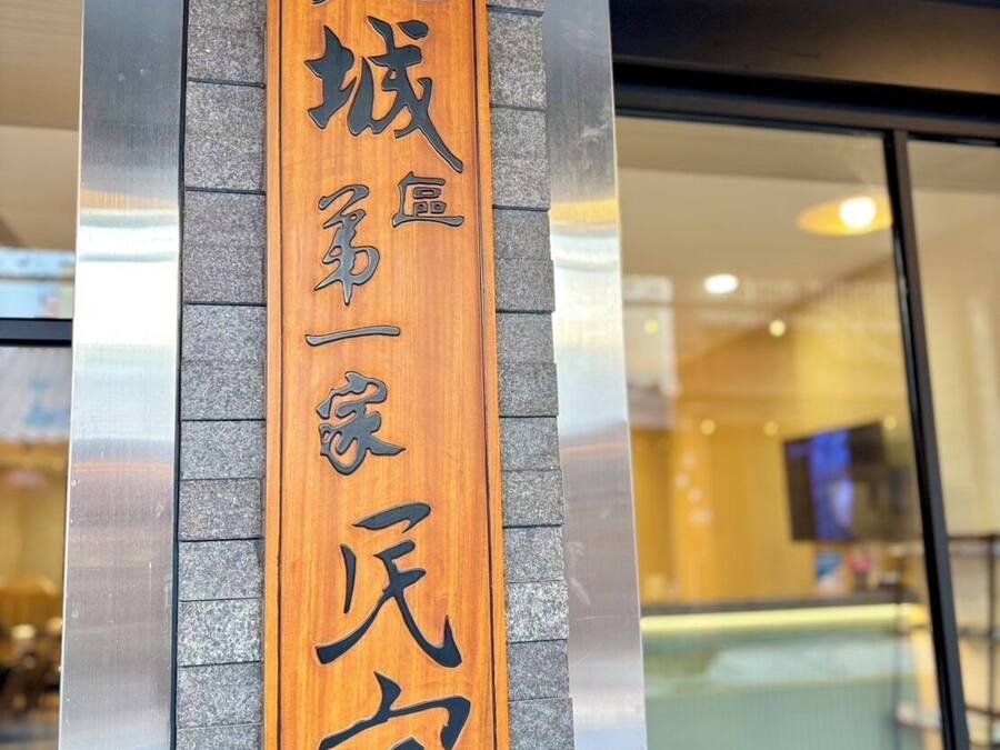 A wooden sign with Japanese characters on a building facade.