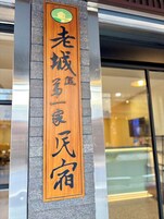 A wooden sign with Japanese characters on a building facade.