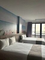 Una habitación de hotel con dos camas, un ventanal con vistas a la ciudad y un balcón con barandilla.