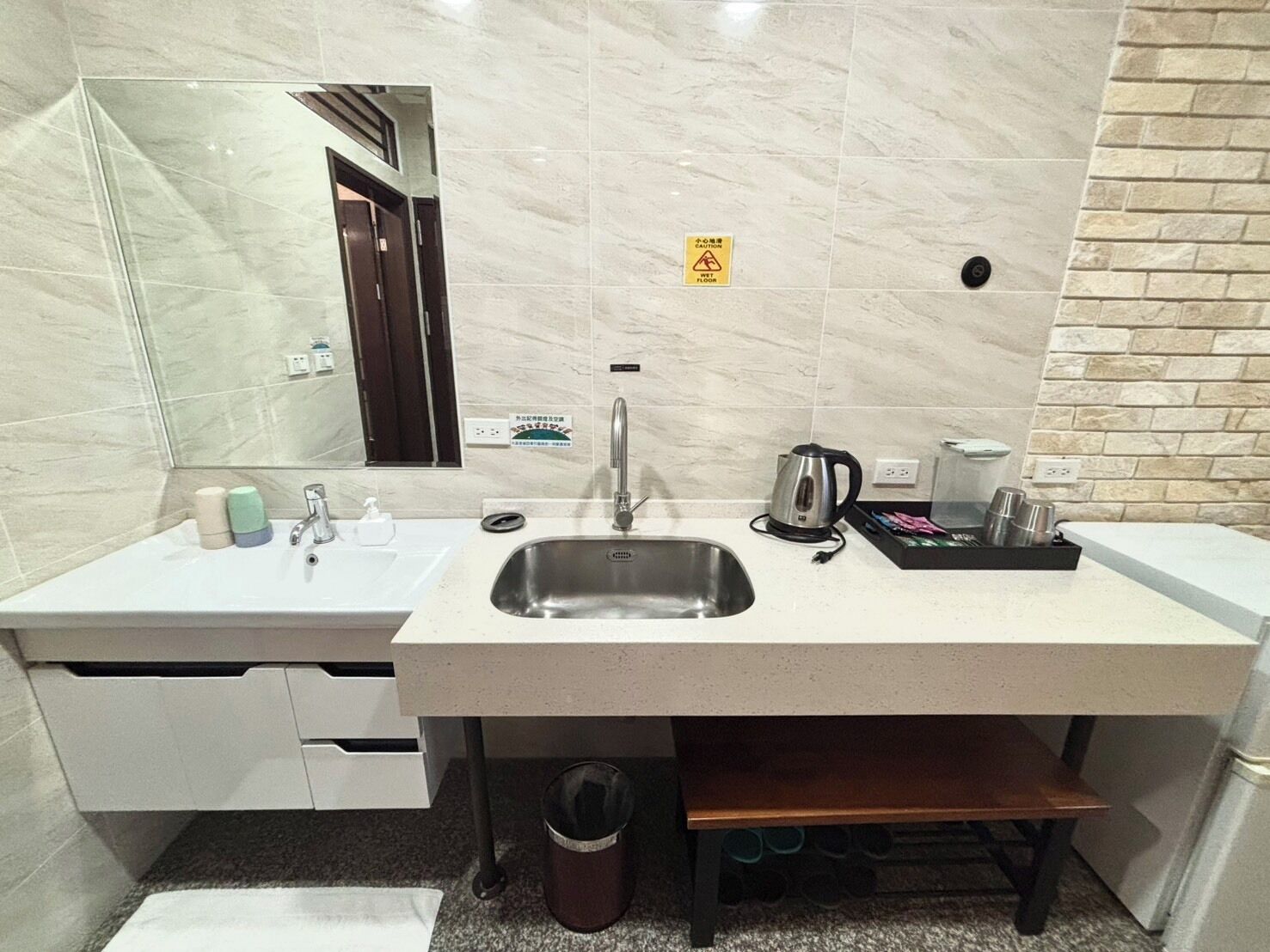 A modern bathroom with a marble floor, a sink with a faucet, a mirror, and a coffee maker.