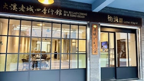 A modern building with large windows and a sign that reads "DAXI LAO CHENG SI JI XING GUAN".