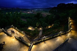 A well-lit outdoor area with a staircase, seating, and a view of a bridge in the distance.