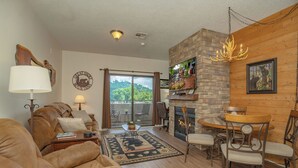 Una sala de estar acogedora con chimenea, asientos confortables y vistas panorámicas a través del ventanal.