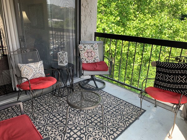 A balcony with a patterned floor, two chairs with red cushions, a small table, and a decorative lantern.