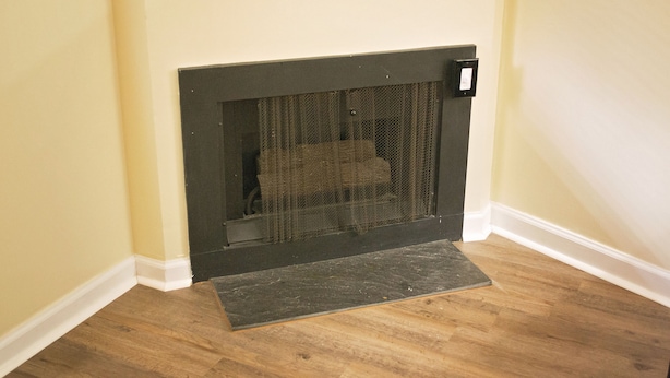 Una chimenea en esquina con protección, un escalón pequeño y un panel de control fijado a la pared.
