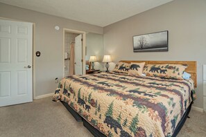 Ein Schlafzimmer mit einem Bett, zwei Nachttischlampen, einer Tür und einem an der Wand hängenden Bild.