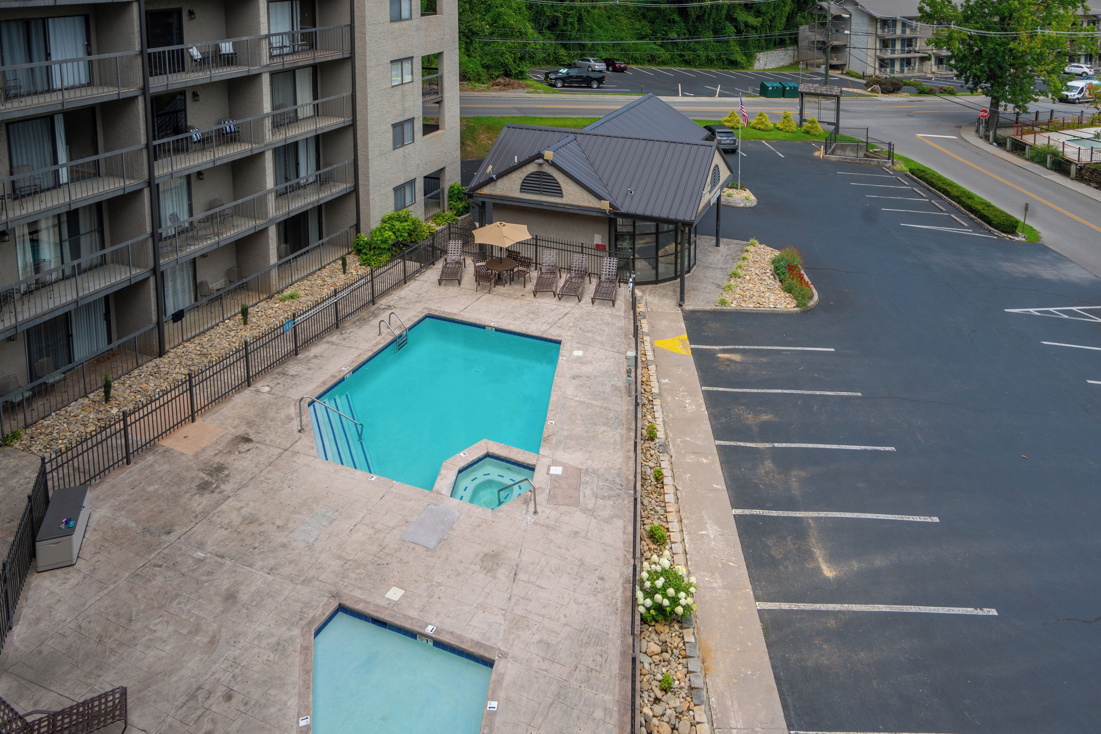 A residential building with a swimming pool, a covered patio, and a parking lot.